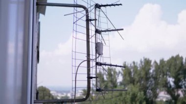 Eski, paslı bir televizyon anteni pencerenin dışındaki bir bilekliğe bağlı. 4K