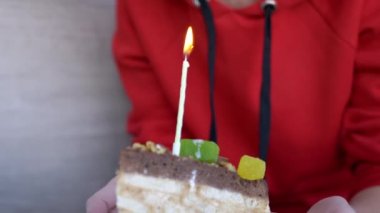 Bir kadın elinde bir tabak dolusu doğum günü pastası ve bir tane yanan mumla tabak tutuyor. 4K