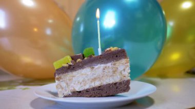 Doğum günü çikolatalı kekinin üzerinde yanan parlak bir mum alevi var.
