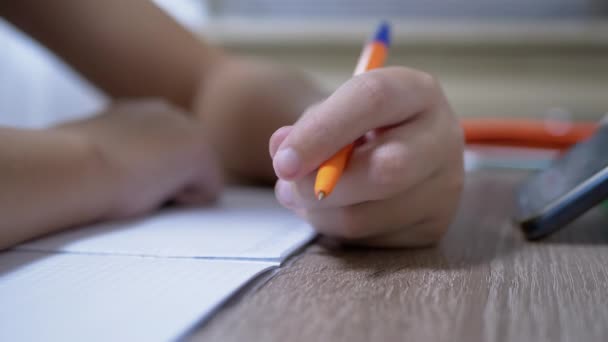 어린이 손은 펜을 노트에 적어 놓고 쓴다. 클로즈업. 4K 입니다. 느린 동작 — 비디오