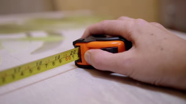 La mano femenina presiona el botón de una cinta metálica naranja con un resorte de retorno — Vídeo de stock