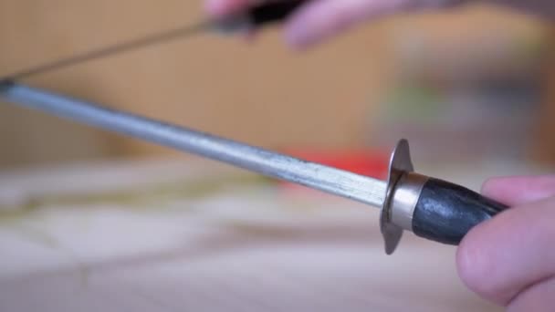मादी हात जुन्या, गलिच्छ, स्वयंपाकघरात स्टील रॉडवर चाकू शार्पेन करतात — स्टॉक व्हिडिओ