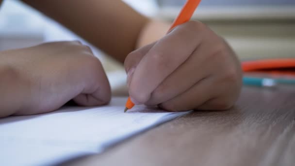 Niño sostiene una pluma en la mano, escribe la tarea en un cuaderno. 4K. De cerca. — Vídeo de stock