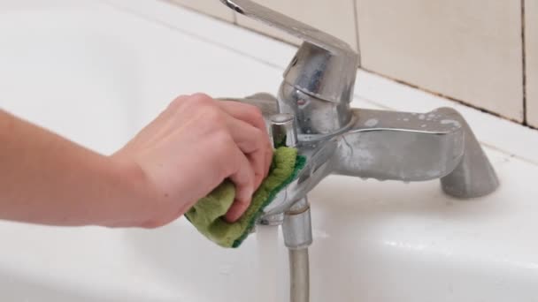 Женская рука чистит грязный кран губкой и детергентом в ванной комнате — стоковое видео