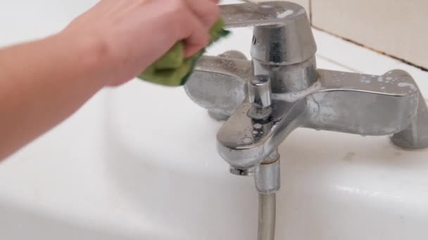 Una mano femenina limpia un grifo sucio con una esponja y detergente en el baño — Vídeos de Stock