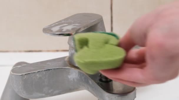 Женская рука чистит грязный кран губкой и детергентом в ванной комнате — стоковое видео