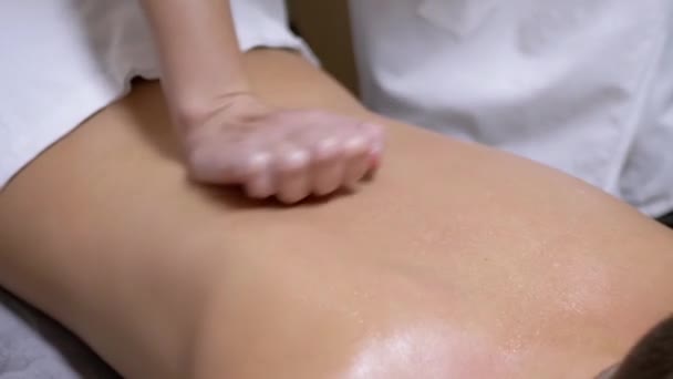 Ręce masażysty masują plecy nastolatka, dziecka w salonie spa. — Wideo stockowe