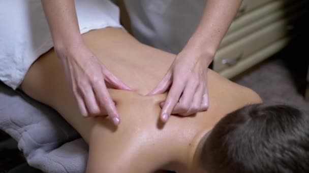 Ręce masażysty masują plecy nastolatka, dziecka w salonie spa. — Wideo stockowe