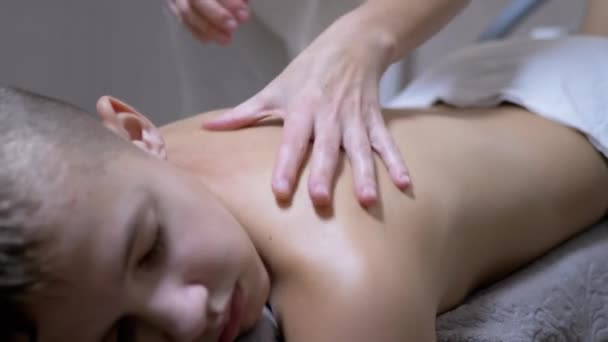 Massør hænder masserer bagsiden af en teenager, et barn i en spa-salon – Stock-video