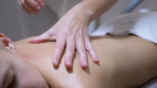 Mãos do massagista estão massageando nas costas de um adolescente, uma criança em um salão de Spa — Vídeo de Stock
