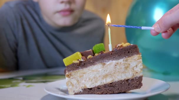 Szczęśliwe dziecko zdmuchuje świeczkę na urodzinowym kawałku ciasta czekoladowego. Powiększenie. — Wideo stockowe