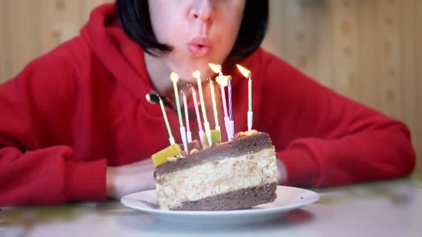 Szczęśliwa kobieta zdmuchuje świeczki na kawałku tortu urodzinowego. Zwolniony ruch — Wideo stockowe