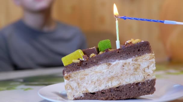 Счастливый ребенок задувает свечу на день рождения кусок шоколадного торта. Zoom. — стоковое видео