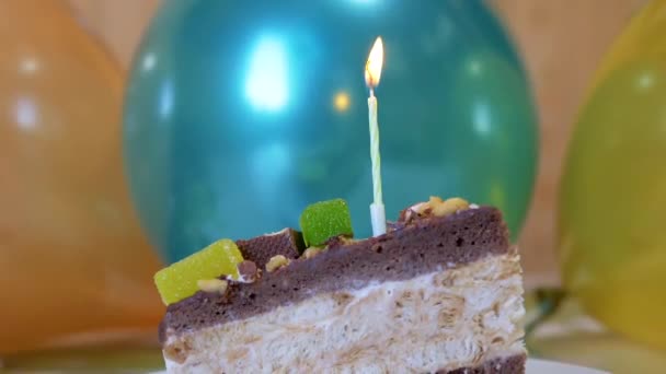 Una llama ardiente brillante de una vela de cera en un pedazo de pastel de chocolate de cumpleaños — Vídeo de stock