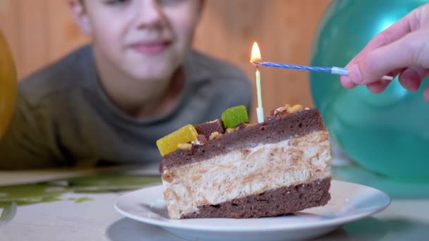 Un niño feliz apaga la vela en un pedazo de pastel de chocolate de cumpleaños. 4K. — Vídeo de stock