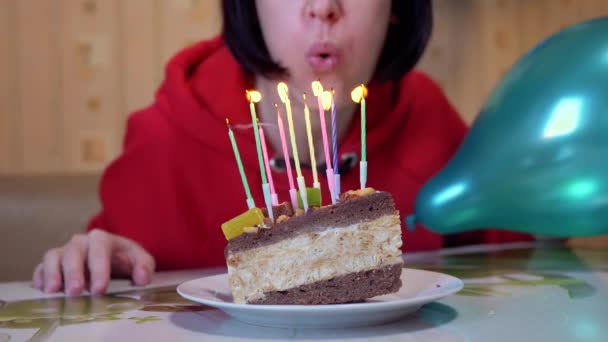 Szczęśliwa kobieta zdmuchuje świeczki na urodzinowym kawałku ciasta. 4K. Zamknij się. — Wideo stockowe