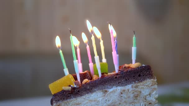 Multicolored Burning Nine Wax Candles on a Chocolate Cake. Close up. Slow motion — Video Stock