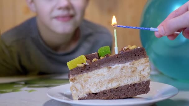 Un enfant heureux souffle la bougie sur un morceau de gâteau au chocolat d'anniversaire. Zoom. — Video
