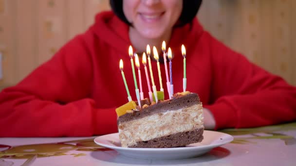 Une fille heureuse regarde brûler des bougies sur un morceau de gâteau au chocolat d'anniversaire. 4K — Video