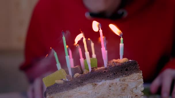 Una mujer sopla velas ardientes en un pedazo de pastel de cumpleaños. De cerca. — Vídeos de Stock