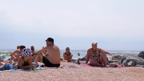 A Group of Tourists are Sitting on the Sandy Seaside, Sunbathing on the Beach — стоковое видео