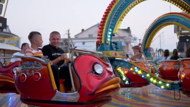 Laughing Father and Teen Sit in Octopus Carousel Waiting for Start. 4K. Close up — Vídeo de Stock