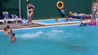 Three Friends, Teenagers Jump in a Transparent Turquoise Pool in the Hotel. 4K