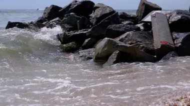 Sea Waves with Foam Bump into Against Rocky Shore of Seashells. Slow motion