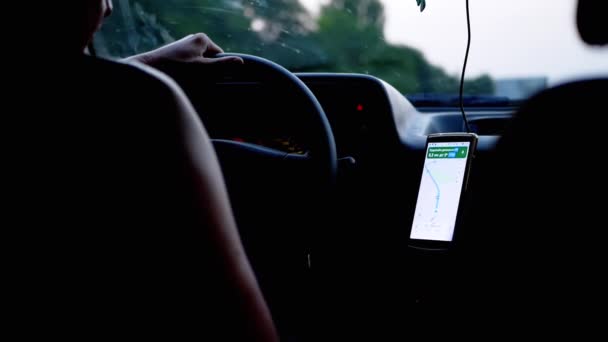Conductor de un automóvil en movimiento utiliza un navegador GPS en un teléfono inteligente en una aplicación móvil — Vídeos de Stock