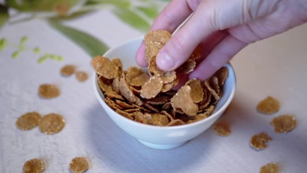 Female Hand Scatters, Pours Out, Throws Corn Flakes into a White Bowl. Close up — Stock Video