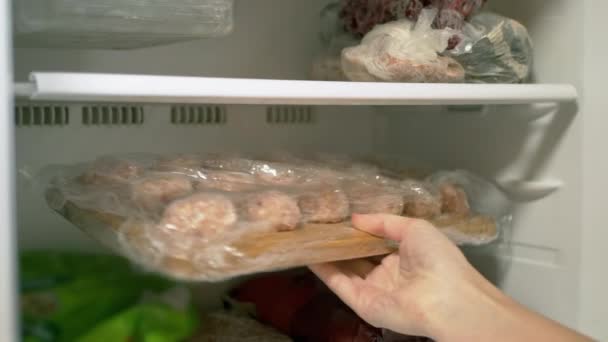 Las manos femeninas sacan productos congelados de carne semiacabada del congelador. 4K — Vídeo de stock