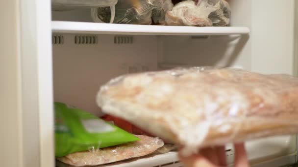 Las manos femeninas ponen productos de carne semielaborados listos en el congelador. De cerca. — Vídeo de stock