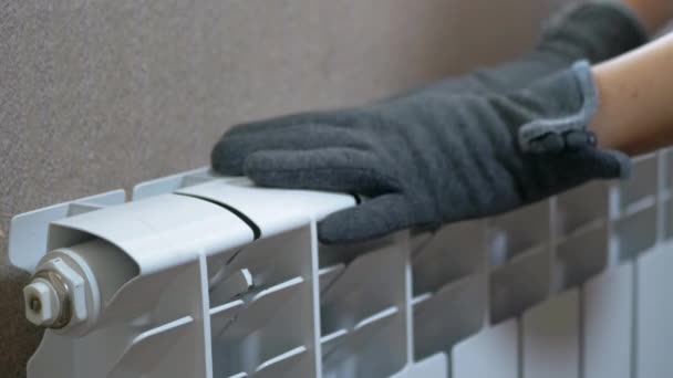 Μια γυναίκα στα μάλλινα γάντια ζεσταίνει τα χέρια σε ένα καλοριφέρ στο σπίτι σε ένα δωμάτιο. Εστίαση — Αρχείο Βίντεο