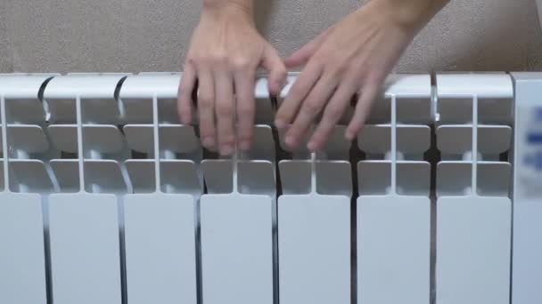 A Female Warms Hands on a Battery, a Heater at Home in a Room. Zoom. Close up — Video