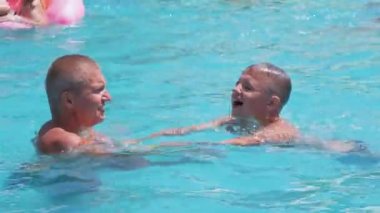 Happy Smiling Father with Son Swim in Open Transparent Swimming Pool. Close up