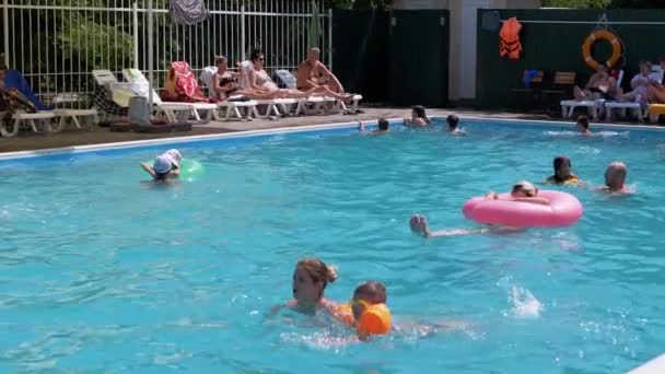 Lots Resting Tourists Swim in Open Transparent Pool on Territory of a Hotel. 4K — Wideo stockowe