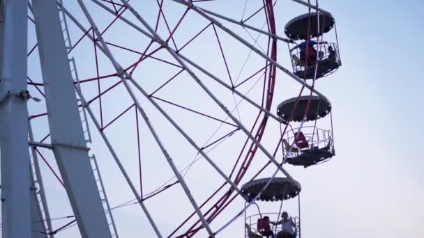 Rotating Ferris Wheel at Sunset in Moon Park with Flickering Lights on Booths — Stockvideo