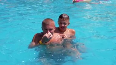 Happy Smiling Father with Son Swim in Open Transparent Turquoise Pool. Close up