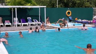 Lots Resting Tourists Swim in Open Transparent Pool on Territory of a Hotel