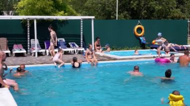 Lots Resting Tourists Swim in Open Transparent Pool on Territory of a Hotel