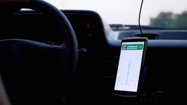 Conductor de un automóvil en movimiento utiliza un navegador GPS en un teléfono inteligente en una aplicación móvil — Vídeos de Stock