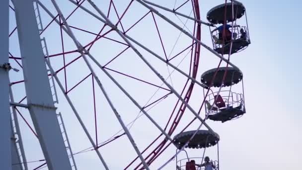 Rotating Ferris Wheel at Sunset in Moon Park with Flickering Lights on Booths — Stock Video