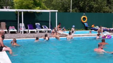 Lots Resting Tourists Swim in Open Transparent Pool on Territory of a Hotel