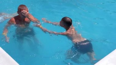 Happy Smiling Father with Son Swim in Open Transparent Swimming Pool. Close up