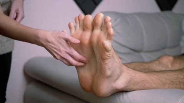 女性の手くすぐる裸の男性の足,つま先,ソファの上に延長.時間の経過 — ストック動画