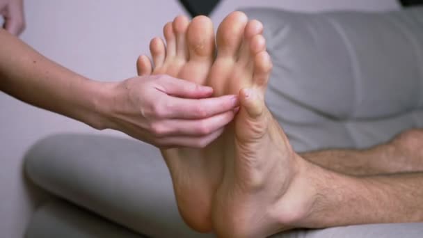 Mãos femininas cócegas pés masculinos nus, dedos dos pés, esticados no sofá. Fechar — Vídeo de Stock