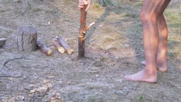 Toeristen op blote voeten hakken hout met een bijl in de natuur in het bos. 4K. Sluiten. — Stockvideo