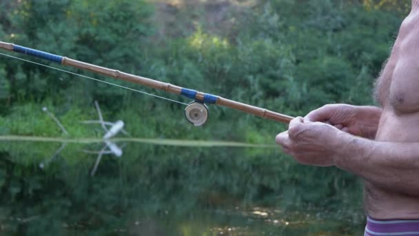 Visser houdt een oude bamboe hengel in armen, rolt een brood bal met vingers — Stockvideo