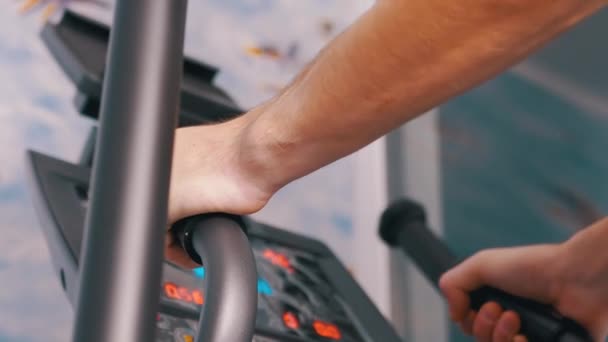 Atleta entrena en un entrenador elíptico en casa, viendo el ritmo cardíaco en el monitor — Vídeos de Stock