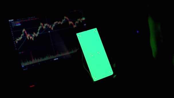 Handlowiec trzyma smartfon z zielonym ekranem w rękach w ciemnym pokoju. 4K — Wideo stockowe